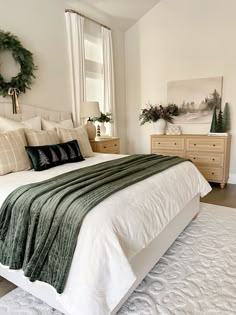 a bedroom with a large bed and wreath on the wall