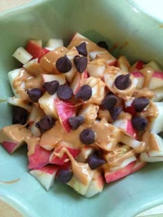 an apple salad with chocolate chips and caramel sauce in a green bowl on a table