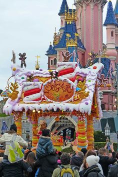 a parade float in front of a castle with lots of people standing around and looking at it