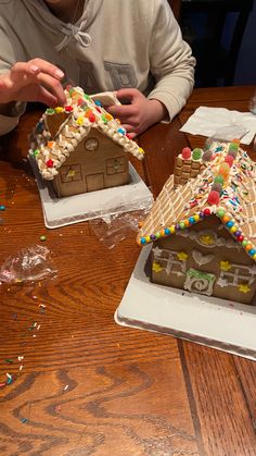 a man sitting at a table in front of two gingerbread houses with sprinkles on them