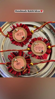 three ornaments with words written on them are placed in a metal bowl and decorated with red tassels