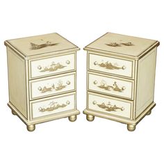 two white chests with gold trimmings on each drawer and one has an image of a boat