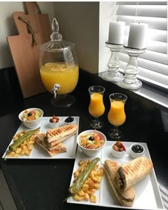 there are three plates with food on them next to glasses of orange juice and an egg carton