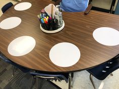 a wooden table topped with lots of white polka dot markers and pens on top of it