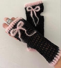 a pair of black and white knitted mittens with pink trims on the fingers