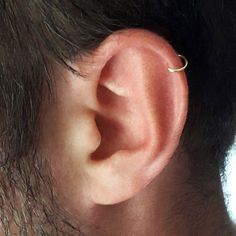 a close up of a man's ear with a single gold ring on it