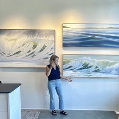 a woman talking on her cell phone in front of some art hanging on the wall