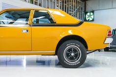 an old yellow car is parked in a garage