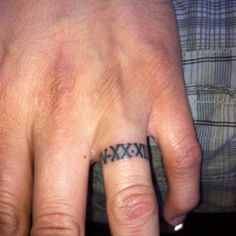 a person with a small tattoo on their left hand and the word xxvix tattooed on his ring finger