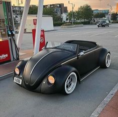 an old black car parked in front of a gas station