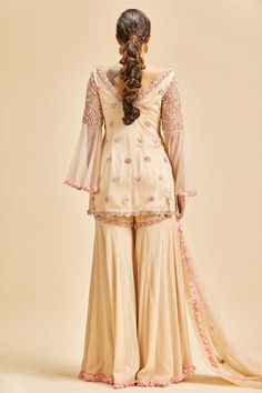 Editor's Note Blush pink embroidered georgette garara with bell sleeved net kurta embroidered in 3D floral pattern with resham, beads and crystals and net dupatta Color: Pink Fabric: Georgette and net Components: Garara, dupatta and kurta Occasion: Wedding guest Disclaimer: Product color may slightly vary due to photographic lighting sources or your monitor setting. Care: Dry Clean Only About the Designer Nitika Gujral’s journey with designing clothes started almost four decades back while she w Georgette Garara, Designing Clothes, Blouse Yoke, Net Embroidery, Pink Kurta, Crystal Embroidery, Sharara Set, Net Dupatta, How To Make Clothes