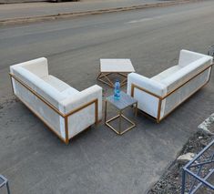 three couches and two tables sitting on the side of the road next to each other