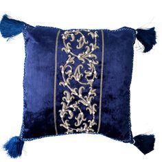 a blue velvet pillow with gold embroidery and tassels on the front, along with a fringe trim