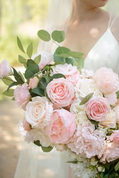 a bride holding a bouquet of pink and white flowers