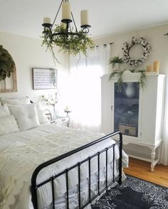 a bedroom with white bedding and black iron bedspread, hanging planters on the wall