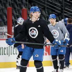 the hockey player is holding his stick and smiling