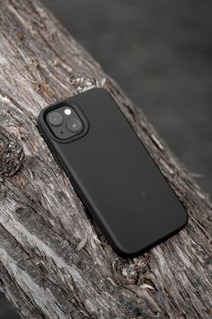 an iphone case sitting on top of a piece of drift wood in front of a tree