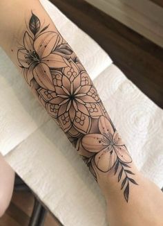 a person with a tattoo on their arm that has flowers and leaves on it,