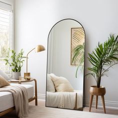 a mirror sitting on top of a wooden floor next to a couch and potted plant