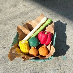 a paper bag filled with assorted vegetables on top of cement floor next to sidewalk