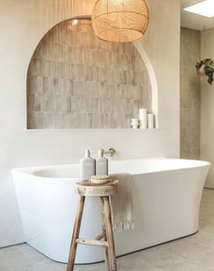 a white bath tub sitting next to a wooden stool