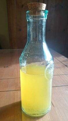 a glass bottle filled with liquid sitting on top of a wooden table