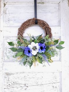 a wreath with blue and white flowers hanging on a door