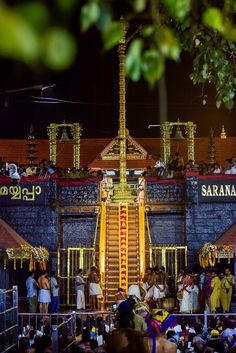 people are gathered in front of a building with stairs and lights on it at night