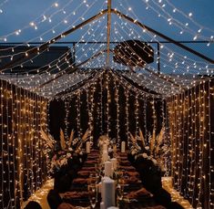 a table with candles and lights on it in the middle of a tented area