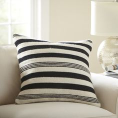 a black and white striped pillow sitting on top of a couch next to a lamp