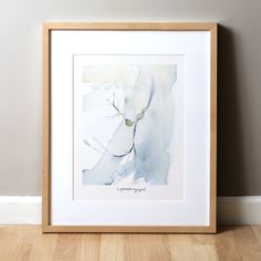 a watercolor painting in a wooden frame on the floor next to a white wall