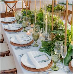 the table is set with place settings and greenery