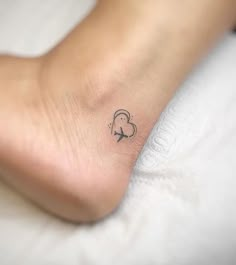 a small tattoo on the foot of a woman's left foot, with a heart and arrow