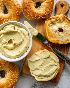 bagels with cream cheese spread on them next to a knife and bowl of dip