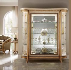 an ornate china cabinet with glass doors and gold trimmings in a living room