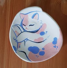 a white cat with pink and blue spots on it's face sitting in a bowl