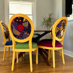 three colorful chairs sitting around a wooden table