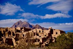 an old adobe village in the desert with mountains in the backgrouds and clouds in the sky