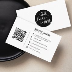 two business cards sitting on top of a black plate next to a cup and saucer