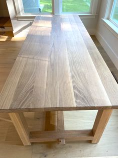 a wooden table sitting in front of two windows