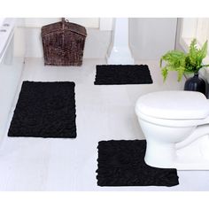 three bathroom rugs on the floor in front of a toilet