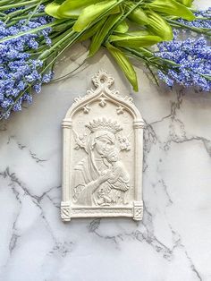 a white plaque sitting on top of a marble counter next to blue flowers and green leaves