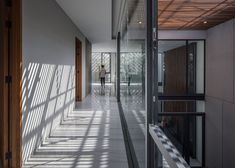 a person walking down a long hallway with lots of light coming in from the windows