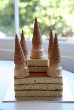 there are four pieces of cake with cones on top of each one, sitting on a table in front of a window