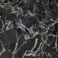 a black and gold marbled surface with a metal object on the ground next to it