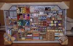 a painting of a sewing shop with lots of thread and spools on the shelves