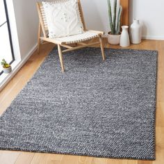 a living room with a chair, rug and potted plant