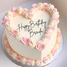 a heart shaped birthday cake with pink and white frosting roses in the shape of a heart