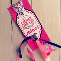 a pink and black ribbon tied to a tag on a wooden surface with the words light up and don't give shine