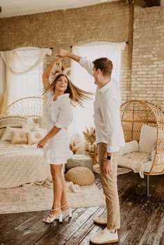 a man and woman dancing in a room with exposed brick walls, wicker furniture and wooden flooring